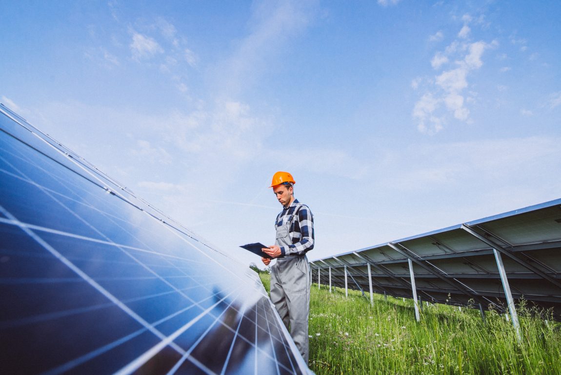 Man worker in the firld by the solar panels Man worker in the firld by the solar panels